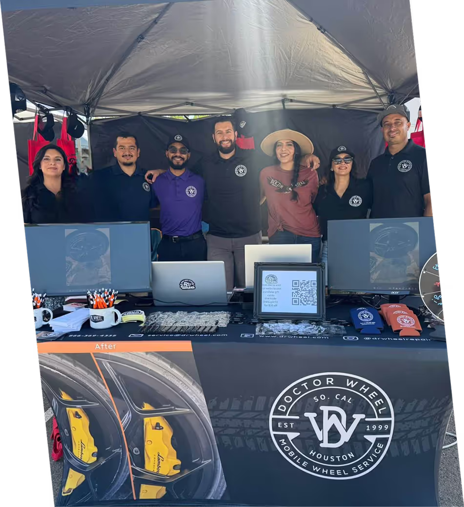 Dr. Wheel team members smiling together at a branded event booth tent